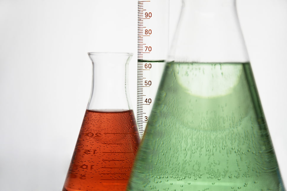 two clear measuring beakers with liquids HD wallpaper
